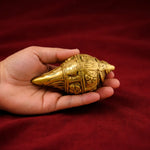 Gold-colored decorative object held in a hand against a red background