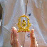 Gold decorative item held by a person against a neutral background