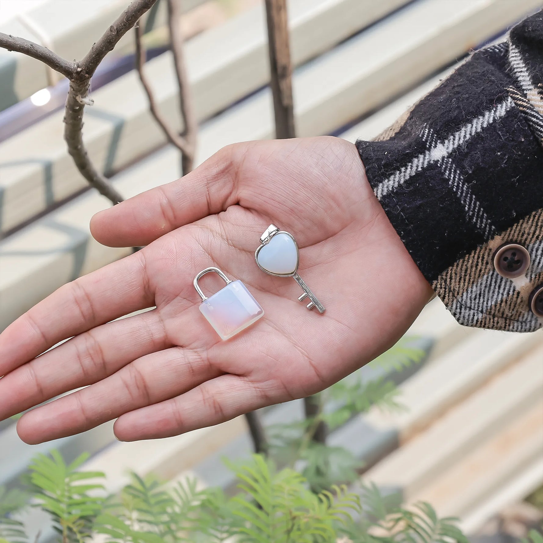 Hand holding a small lock and key with a blurred outdoor backgroundOpalite Lock And Key Pendant - Abhimantrit & Certified