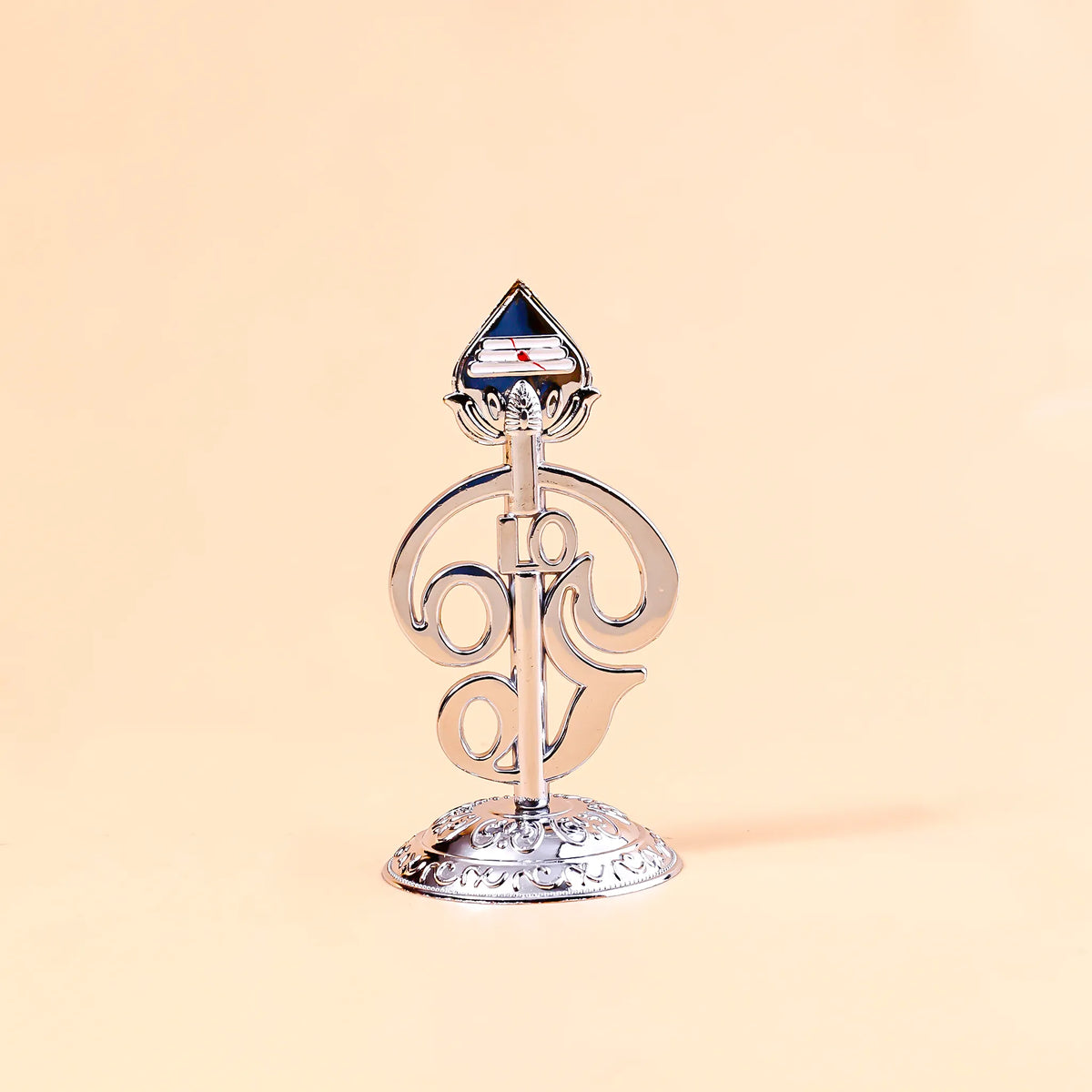 Decorative metal object with a blue gem on a beige background