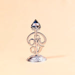 Decorative metal object with a blue gem on a beige background