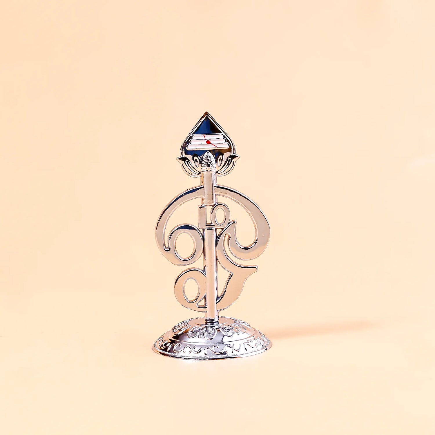 Decorative metal object with a blue gem on a beige background