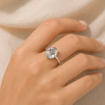 Hand wearing a ring with a large diamond on a neutral background