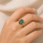 Hand wearing a green ring on a beige background