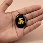 Black stone with a gold dragon design held in a hand against a beige background