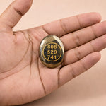 Hand holding a small stone with engraved numbers on a beige background