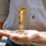 Gold curved object held in a hand with a blurred background
