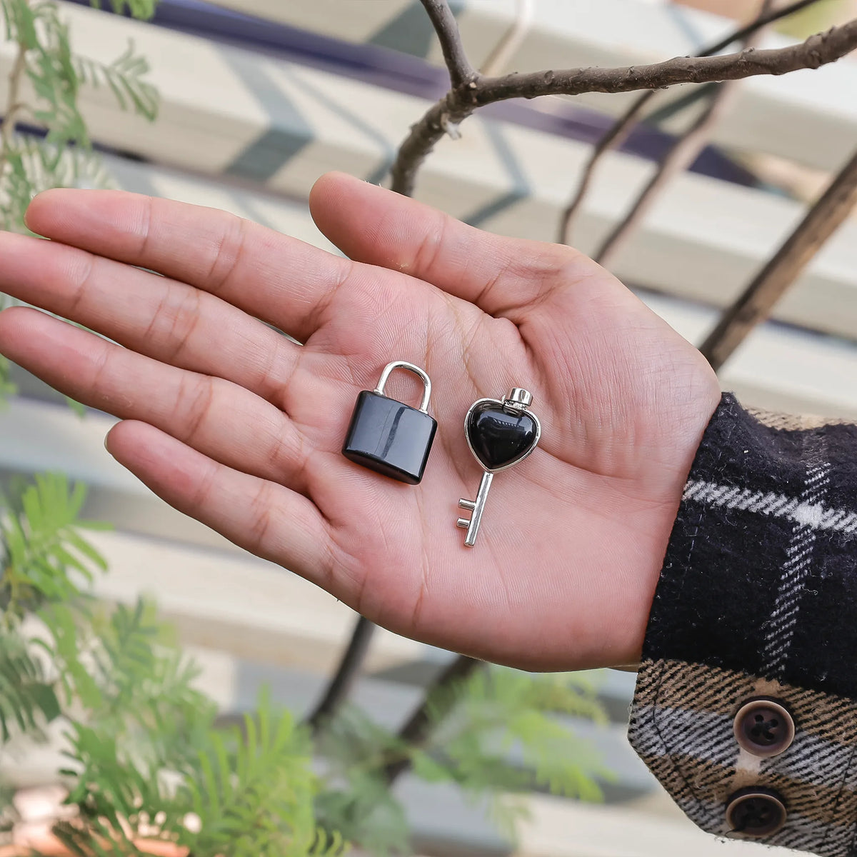 Hand holding a small padlock and key against a blurred outdoor background