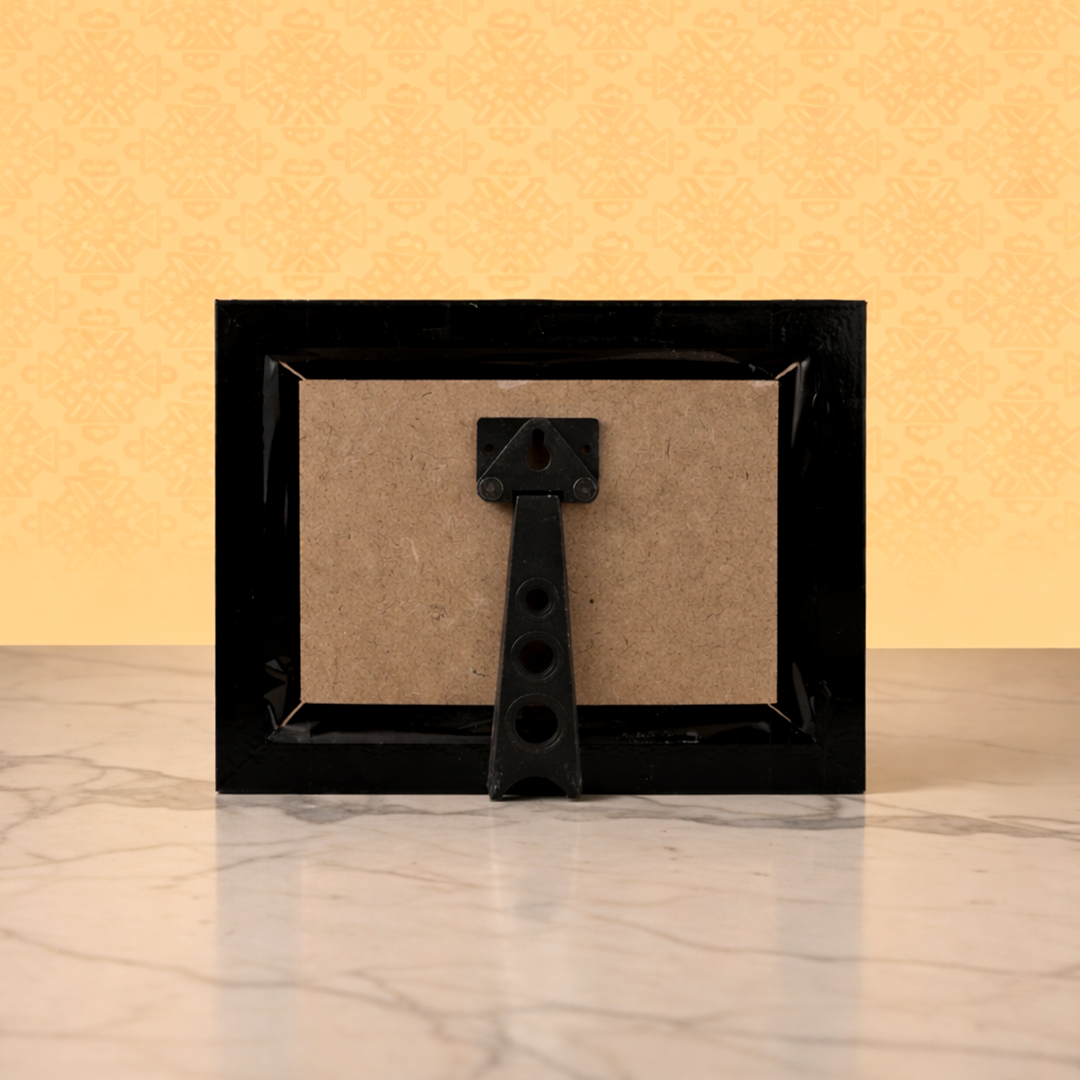 Black picture frame with a decorative accent on a marble surface and yellow wall background