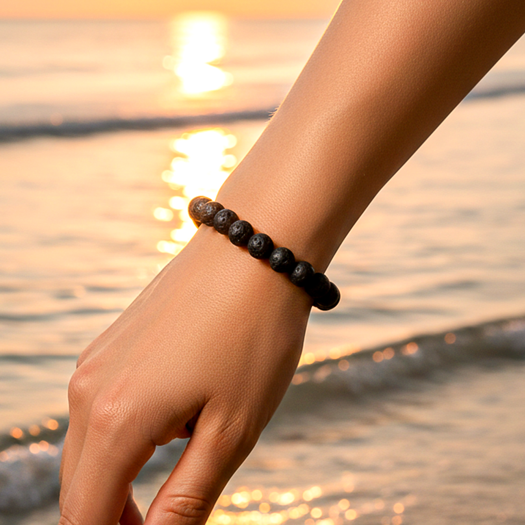 Hand wearing a black beaded bracelet with a sunset over water in the backgroundLava Stone Bracelet - Grounding & Protection Energy Bracelet