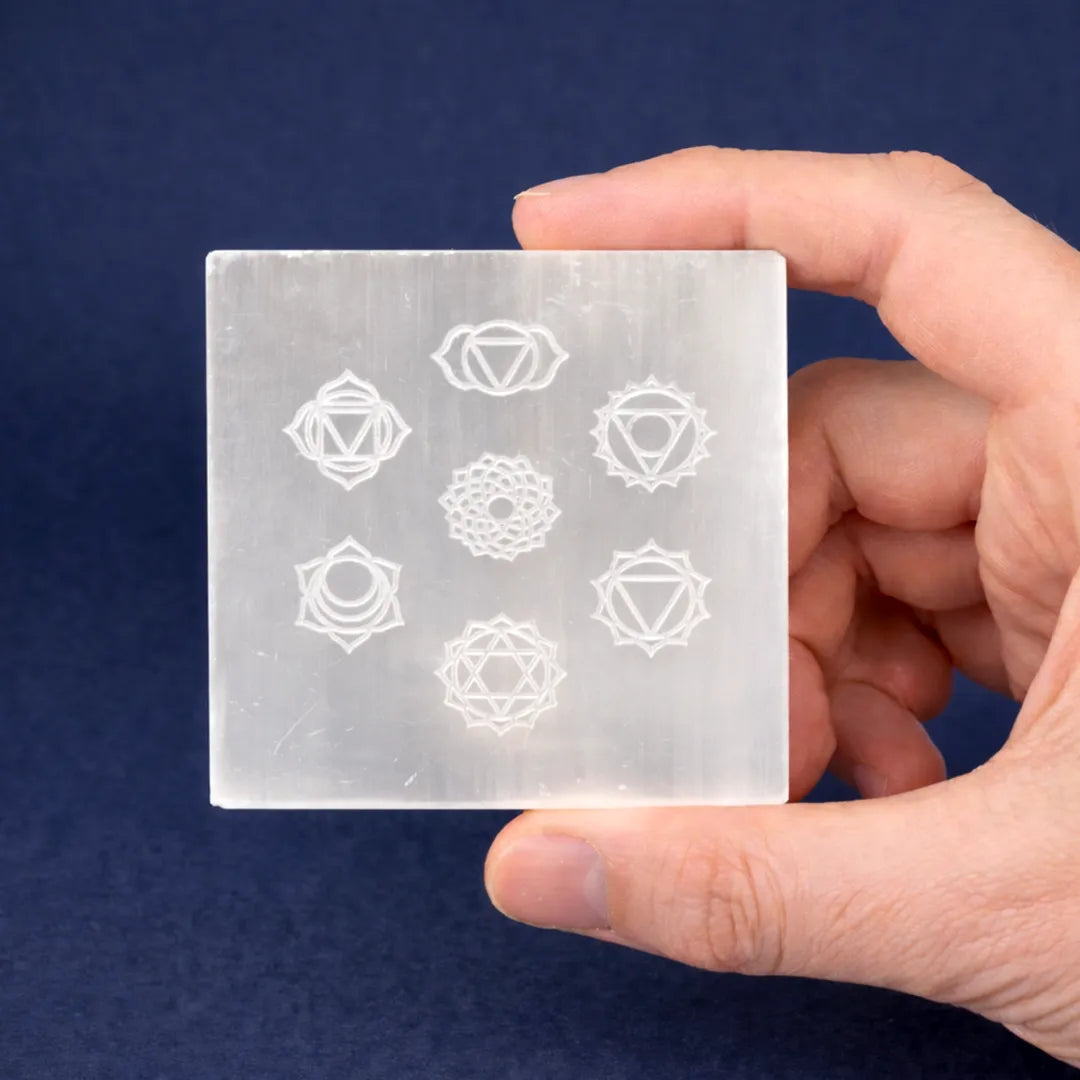 Hand holding a crystal with white symbols on a dark blue background