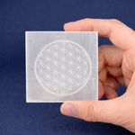 Hand holding a square piece of paper with a white geometric design against a blue background