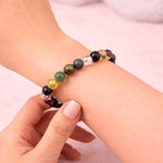 Multicolored beaded bracelet on a wrist against a light background