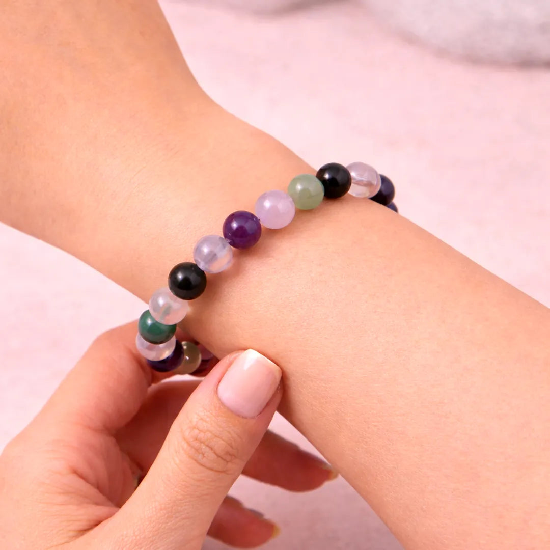 Multicolored beaded bracelet on a wrist with a plain background