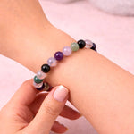 Multicolored beaded bracelet on a wrist with a plain background