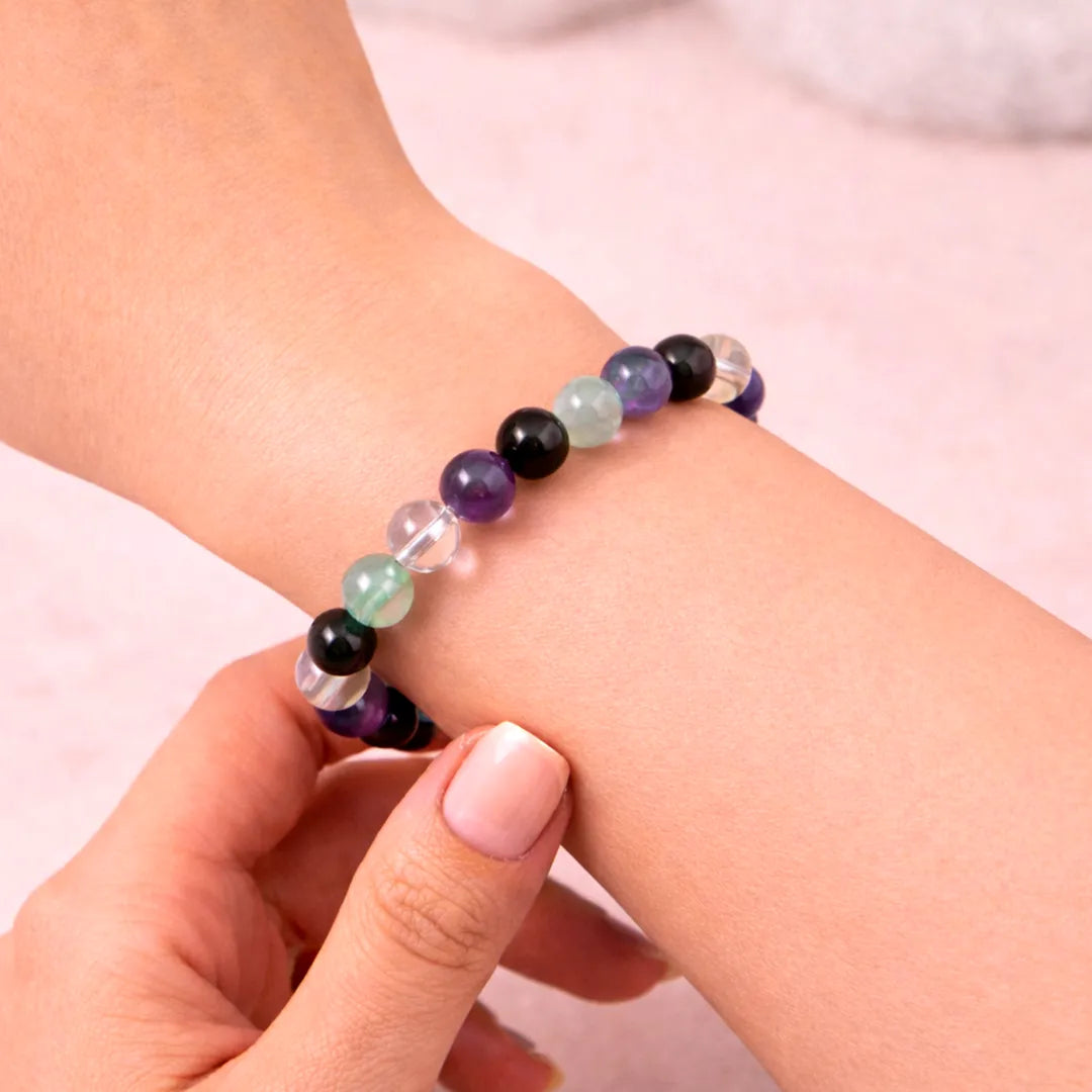 Multicolored beaded bracelet on a wrist with a plain background