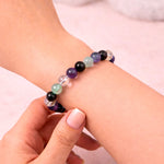Multicolored beaded bracelet on a wrist with a plain background