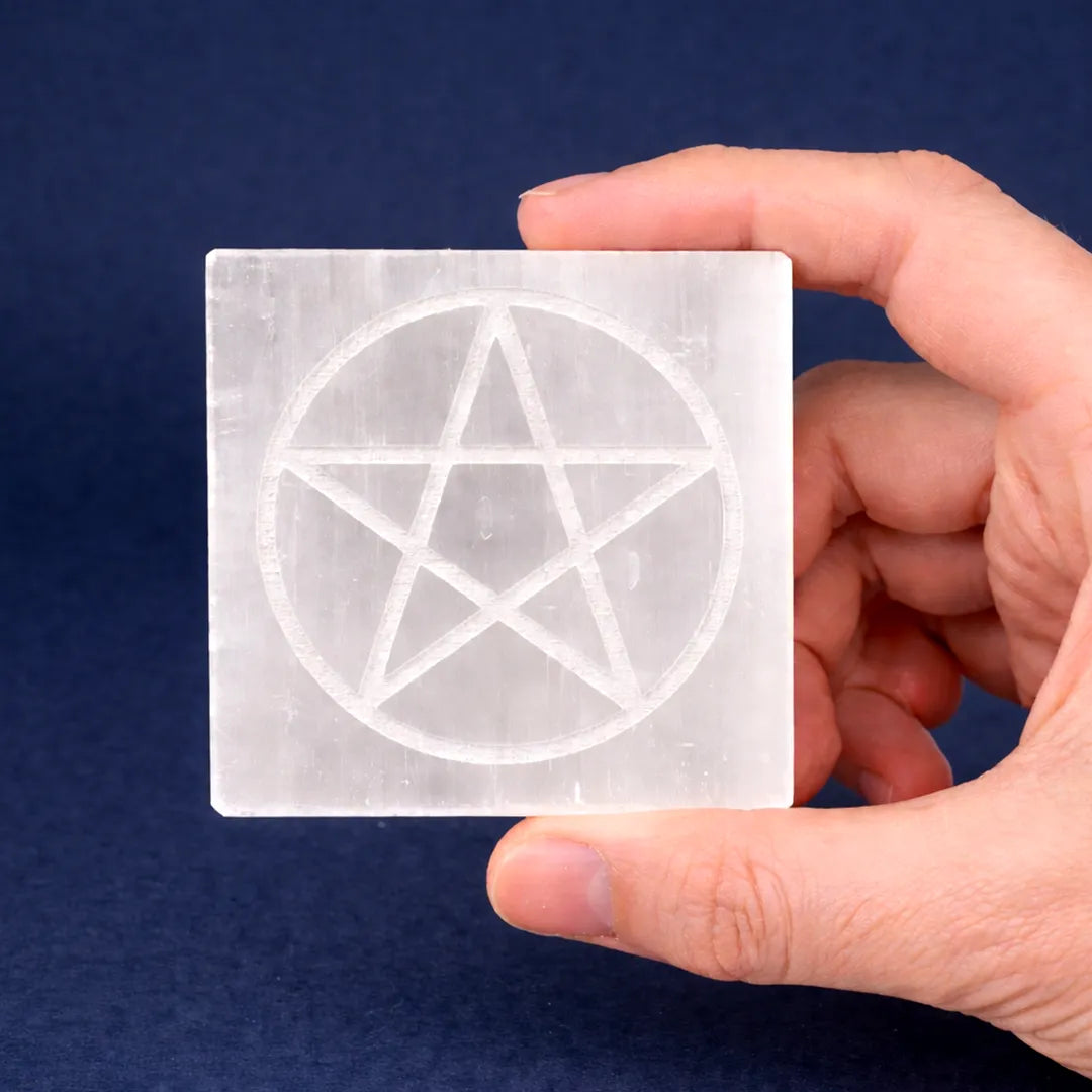 Hand holding a square piece of paper with a pentagram symbol against a blue backgroundSelenite Star Plate Square – Energized Crystal Charging & Energy Cleansing Plate