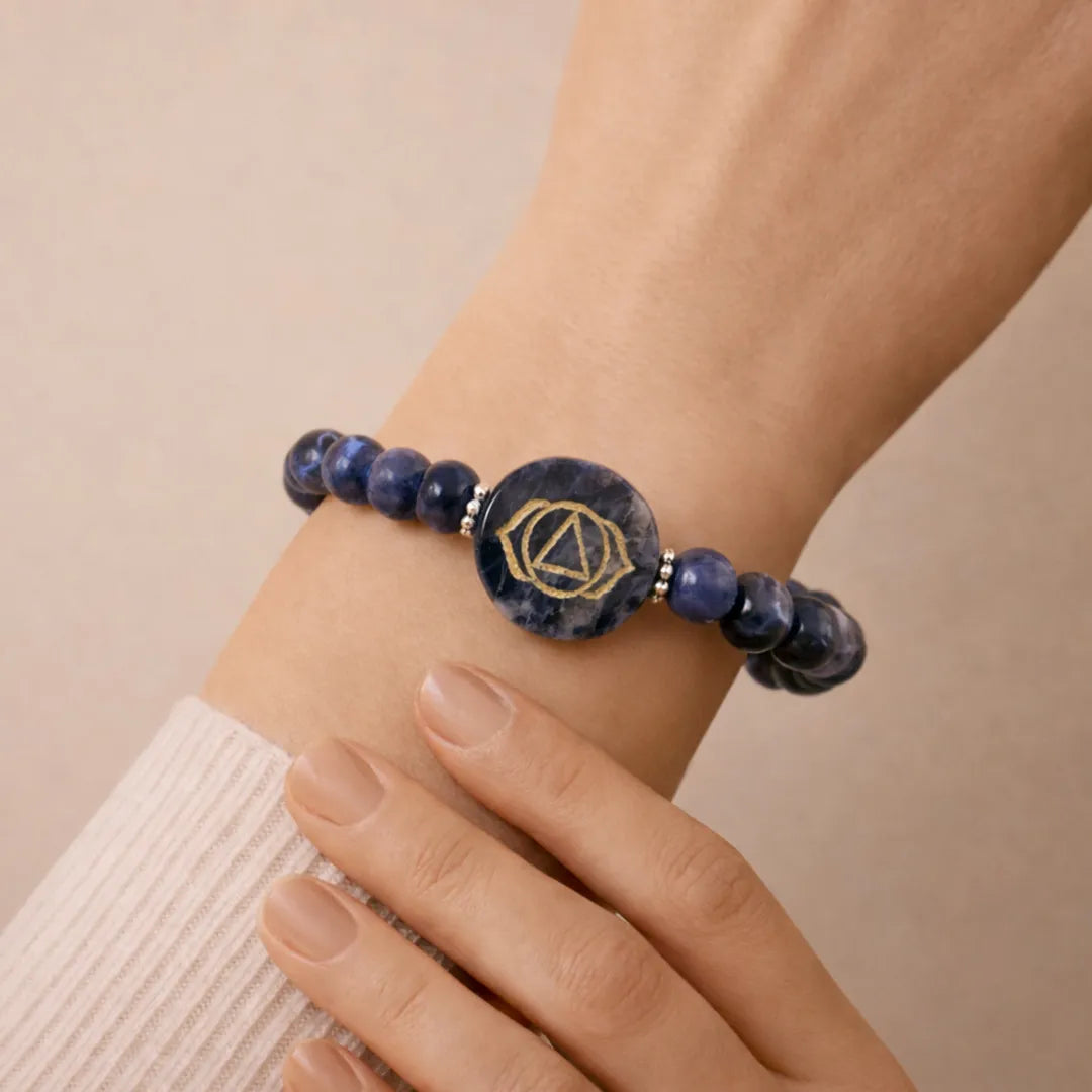 Bracelet with blue beads and a central stone on a wrist against a beige background
