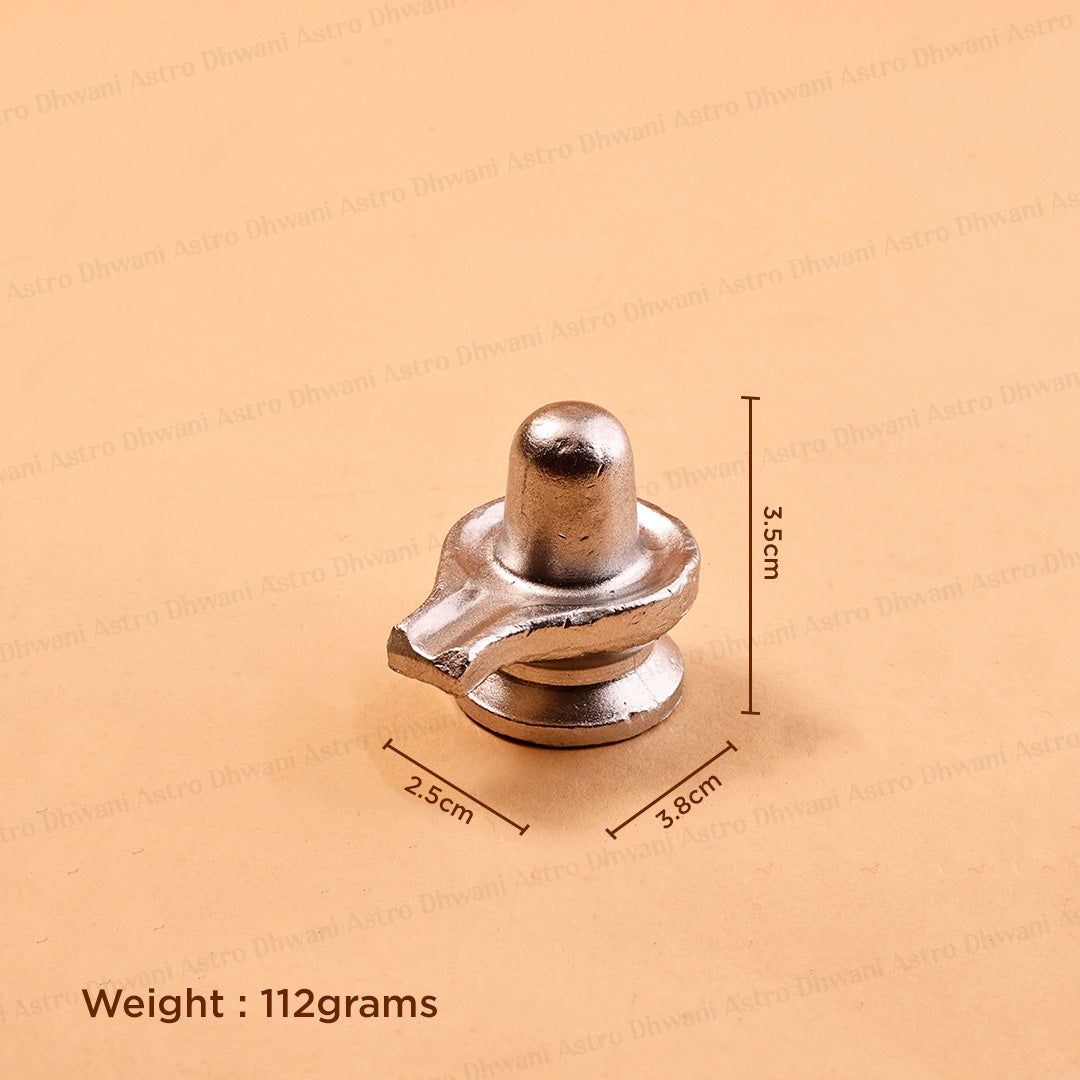 A small metallic silver object, likely a decorative or functional hardware piece, shown on a beige background with dimensionsParadeshwar Shivling | Shiva Lingam for Puja & Abhishek | Sacred Idol
