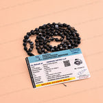A black and white banded stone mala necklace is displayed on a peach-colored background next to its official certificate card.