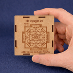Hand holding a wooden card with Sanskrit text and a symbol on a blue background
