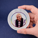 Hand holding a round photo card with a person's face on a blue background