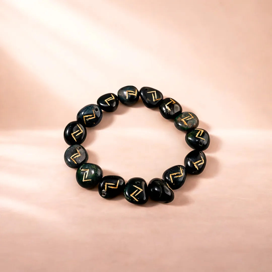 Black beaded bracelet with gold patterns on a pink background