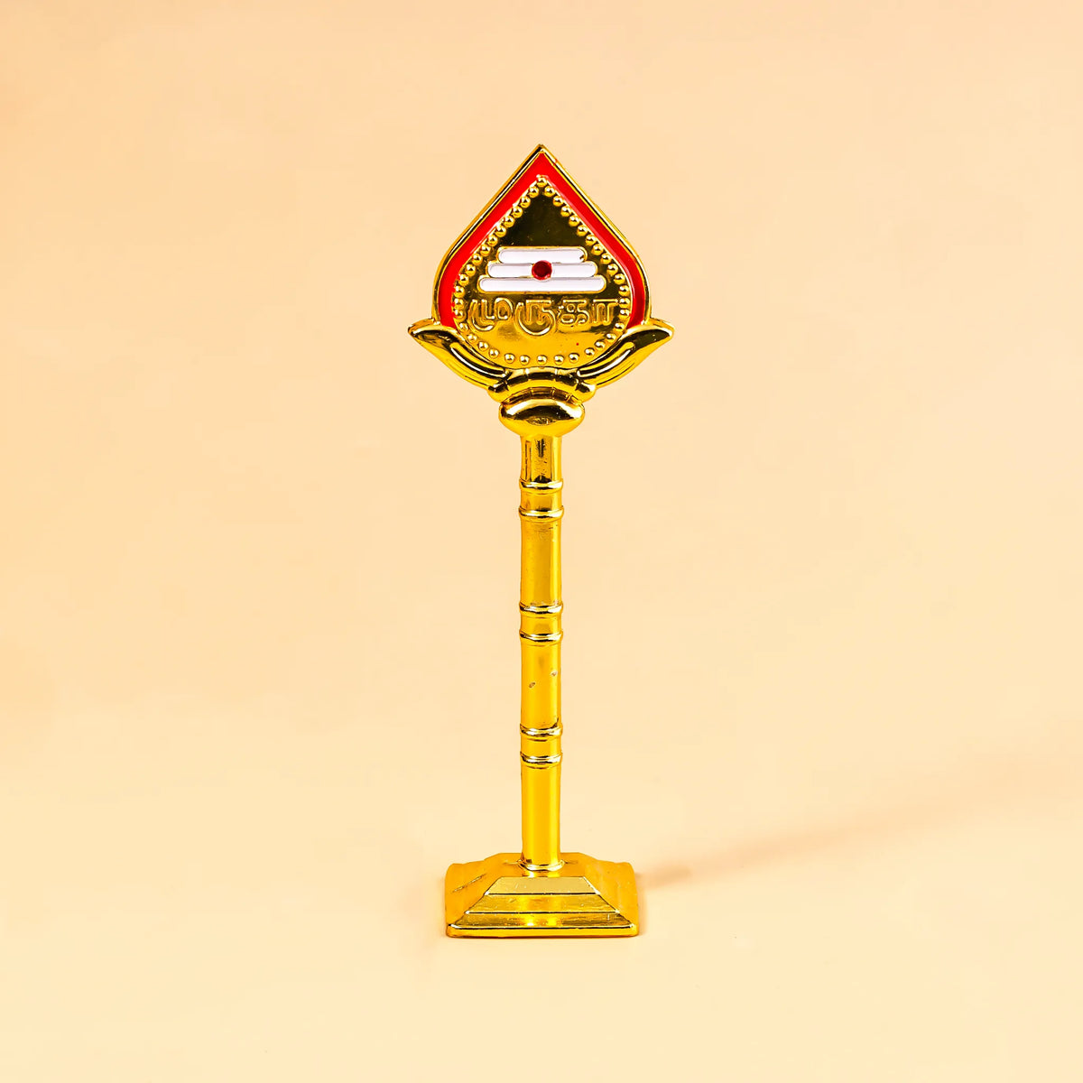 Decorative object with a red top and gold body on a beige background