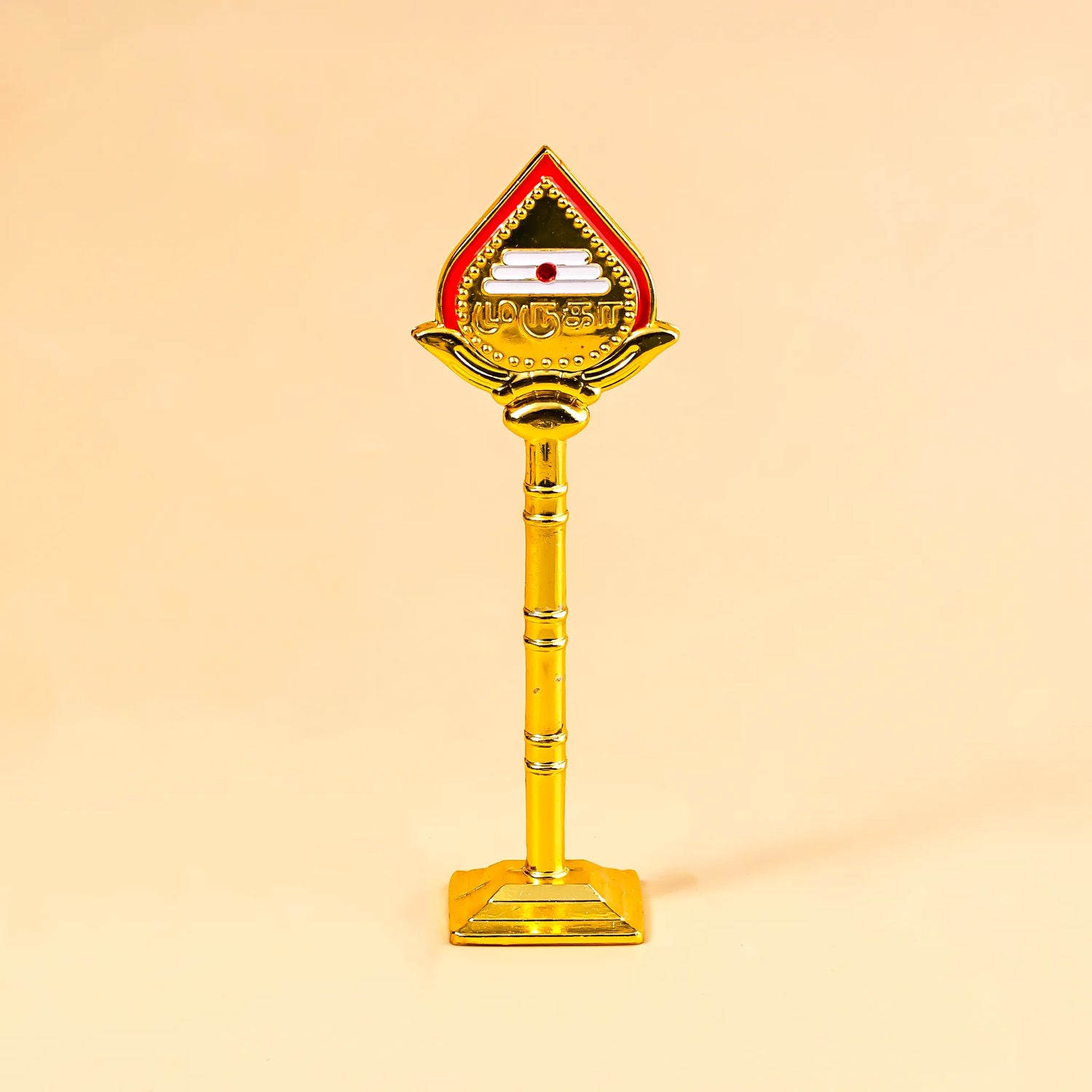 Decorative object with a red top and gold body on a beige background