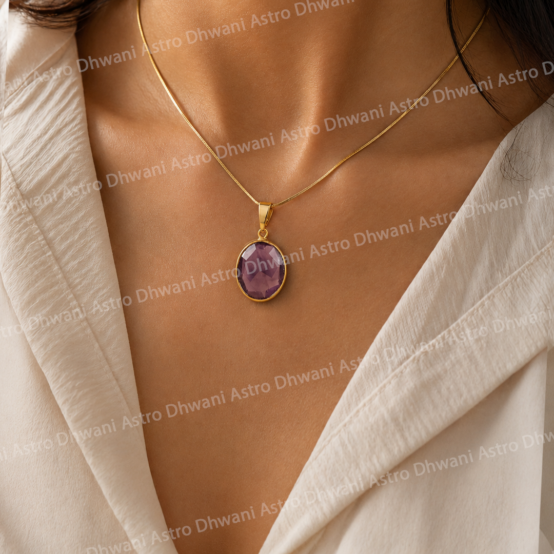 Gold necklace with a purple pendant on a person wearing a white top.