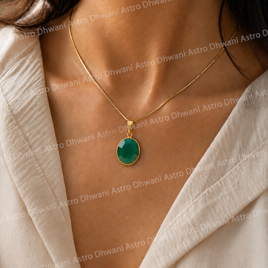 Gold necklace with a green pendant on a person wearing a beige garment.