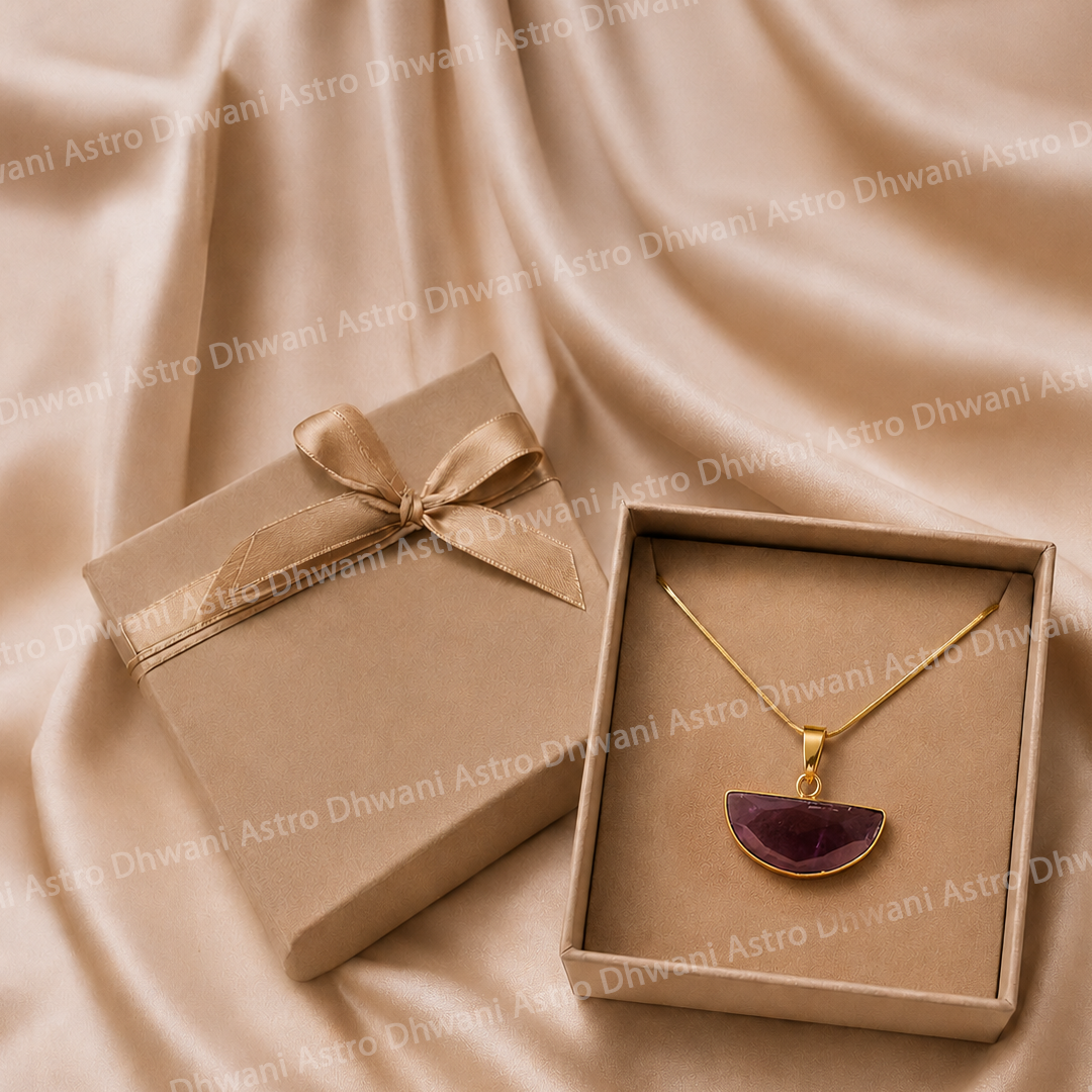 Gold necklace with a purple pendant in an open box on a beige fabric background