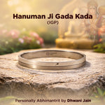 Silver bracelet on a stone surface with a blurred background of a statue and flowers.