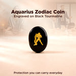 Black tourmaline coin with Aquarius zodiac symbol on a blurred background of people.