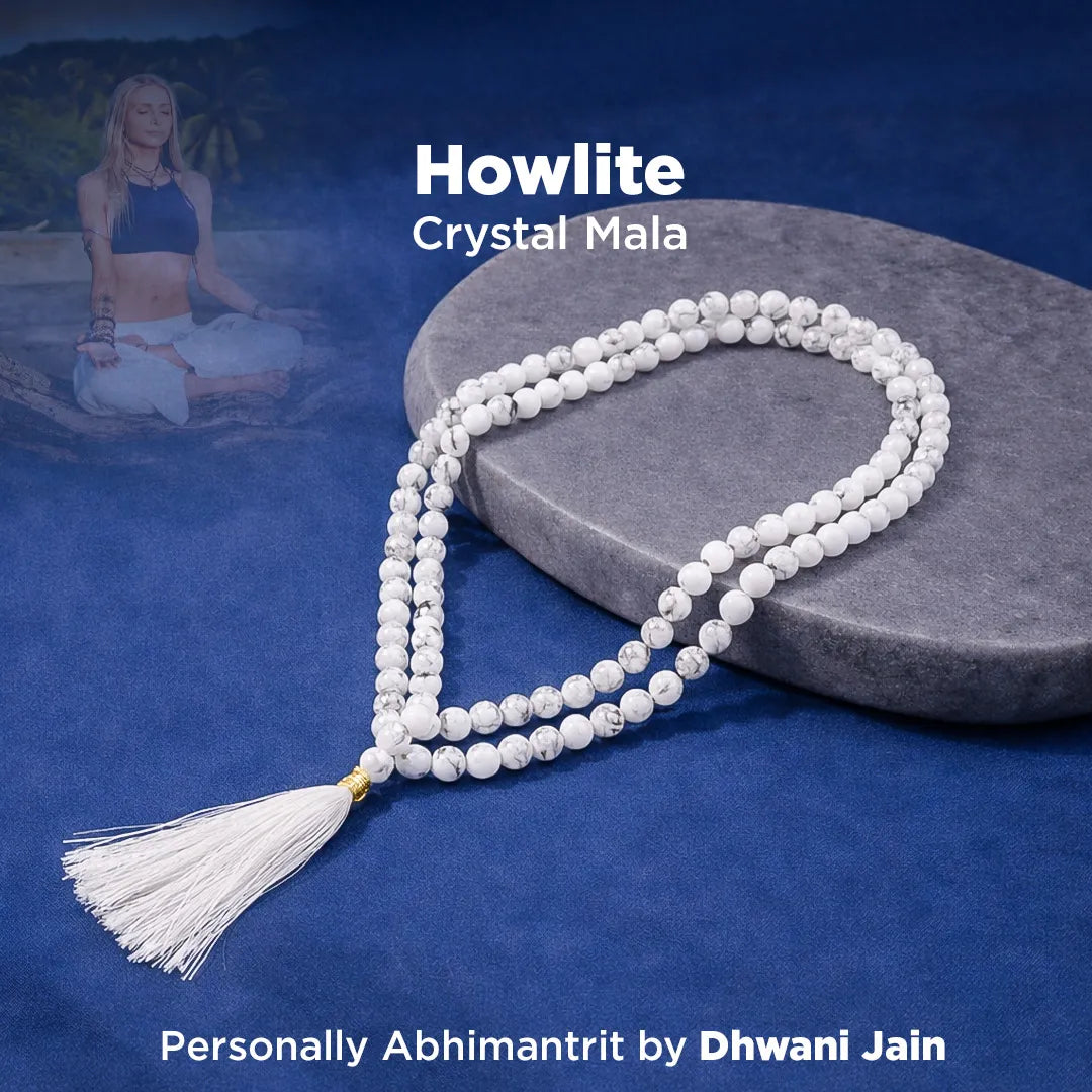 Howlite crystal mala necklace with tassel on a blue background, person meditating in the background.