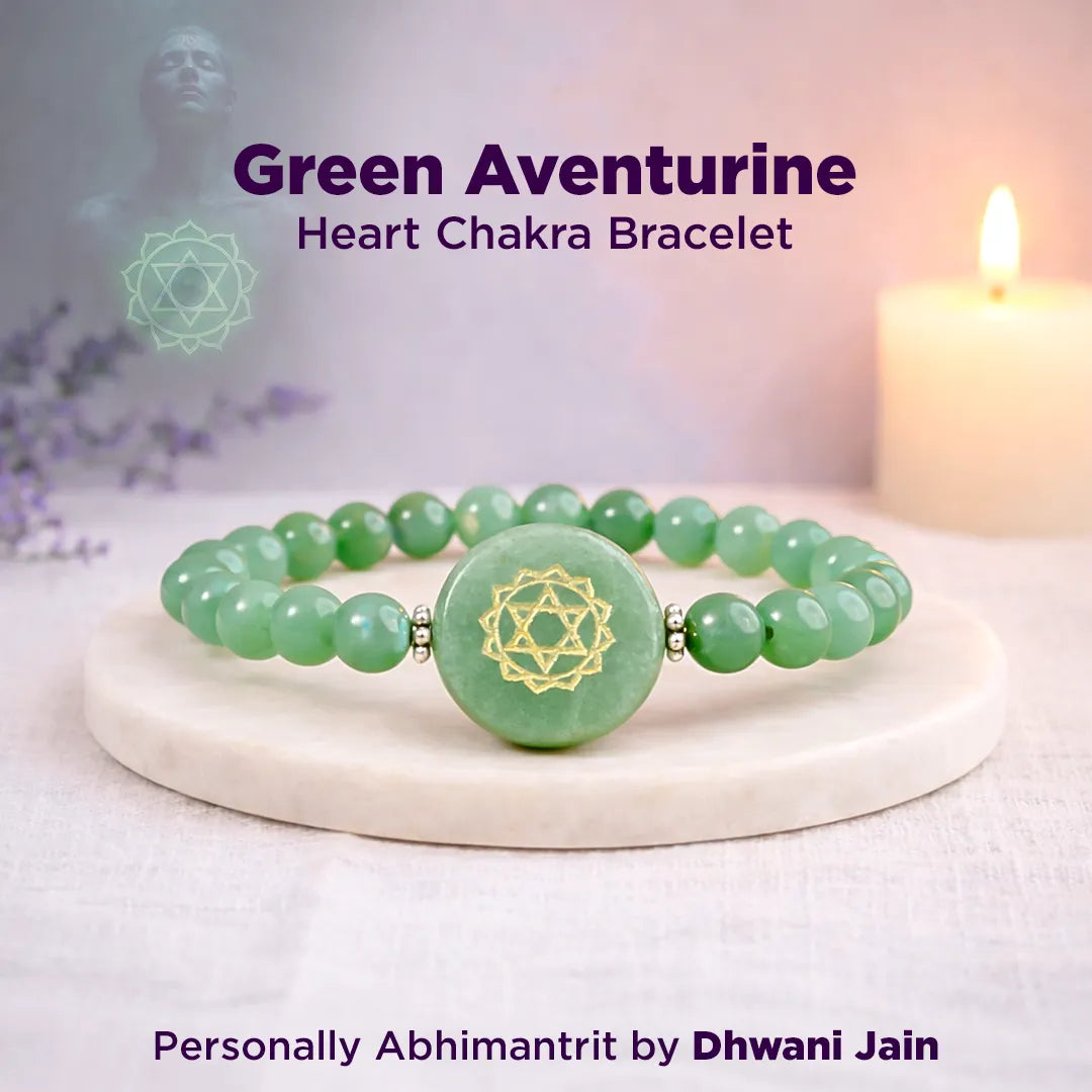 Green aventurine heart chakra bracelet on a white surface with a candle in the background