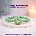 Green aventurine heart chakra bracelet on a white surface with a candle in the background