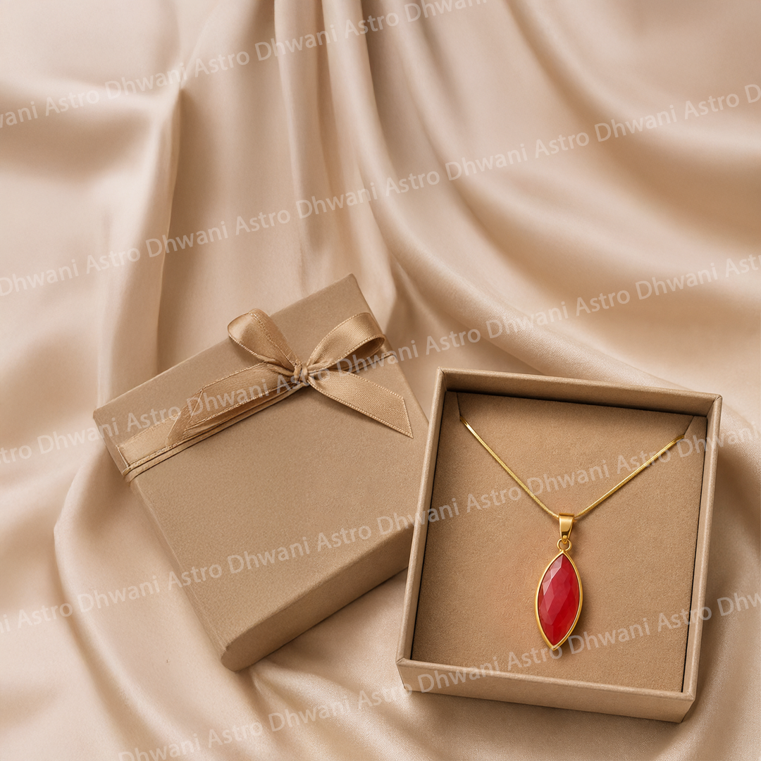 Gold necklace with a red pendant in an open box on beige fabric