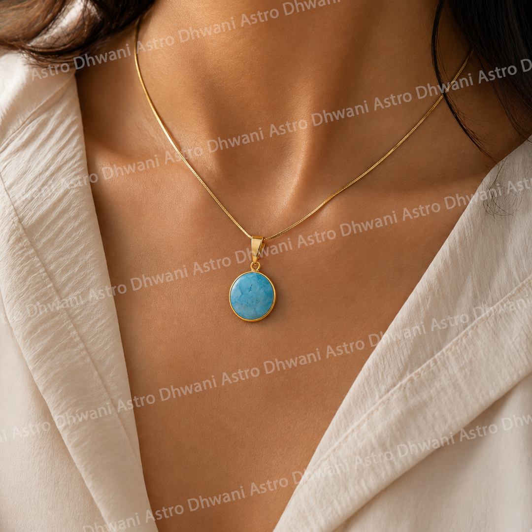 Gold necklace with a blue pendant on a person wearing a beige outfit.Round Turquoise Aura Pendant in Real 24KT Gold with Luxury Crystal