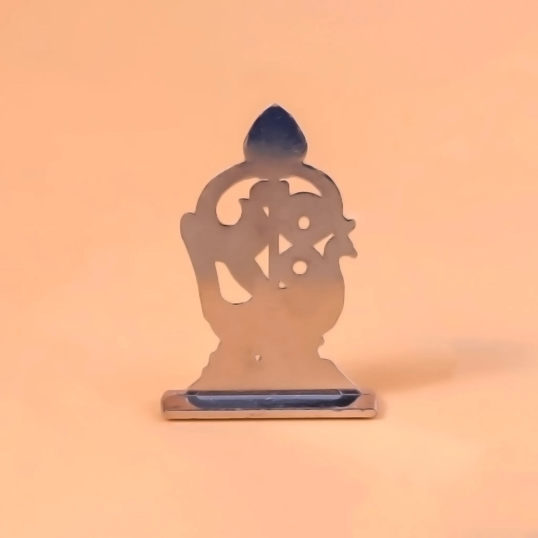 Metallic sculpture of a seated figure on an orange backgroundMurugan 1 Peacock Vel – Abhimantrit & Certified