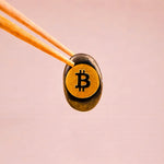 Bitcoin symbol on a coin held by tweezers against a pink background
