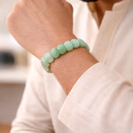 Person wearing a light green beaded bracelet on a blurred background