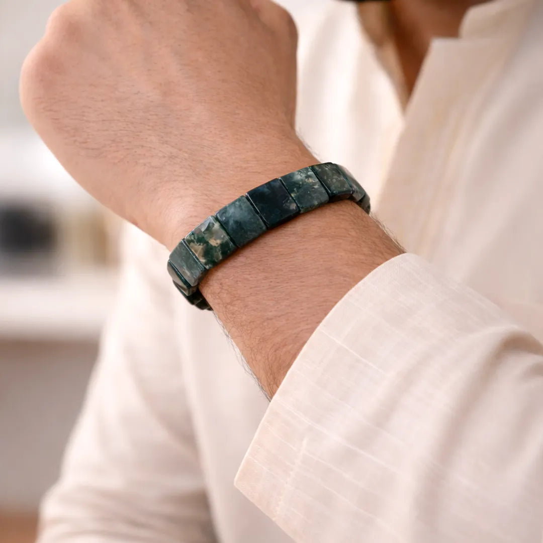 Person wearing a green stone bracelet on a blurred backgroundMoss Agate Emerald Cut Bracelet – Growth, Stability & Emotional Balance