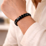 Black beaded bracelet on a wrist with a blurred background