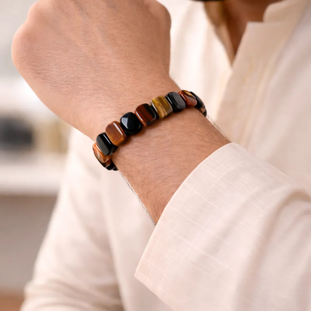 Close-up of a person wearing a beaded bracelet on a blurred indoor backgroundMulti Tiger Eye Emerald Cut Bracelet – Strength, Focus & Protective Power Wear