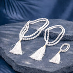 White beaded necklace with tassels on a dark stone surface