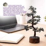 Pyrite crystal tree on a desk with a laptop and notebook, text about pyrite crystal properties.