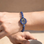 Blue beaded bracelet with a circular design on a wrist against a beige background