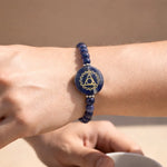 Blue beaded bracelet with a circular design on a wrist against a beige background